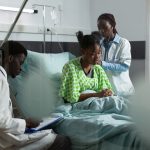african-american-medical-team-working-healing-patient-hospital-ward-bed-man-woman-with-doctors-occupation-examining-young-adult-treatment-using-monitor-stethoscope_482257-16510